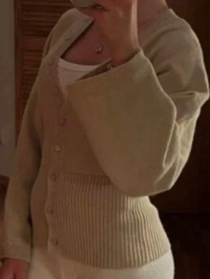 Beige ribbad kofta med knappar - Helt ny, aldrig använd! Populär trendig beige kofta med knappar framtill och ribbad midja. Storlek S.