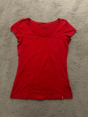 Röd t-shirt från edc - En enkel och stilren röd t-shirt från edc med rund halsringning och korta ärmar. Tillverkad i mjuk bomull som känns skön mot huden. Passformen är lite lös vid midjan på mig som brukar ha s