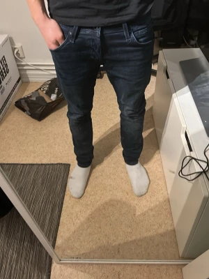 Mörkblå slim fit jeans herr - Snygga mörkblå slim fit jeans. Jeansen har en lätt tvättad som är riktigt snygg. Storlek 30/30 modell slim glenn.  modellen är runt 174cm lång, säljer de billigt för att bara vill få de sålda behöver pengar