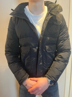 Svart Woolrich pufferjacka med fickor - Säljer denna svarta woolrich pufferjack Perfekt för kalla vinterdagar och riktigt skön att bära.