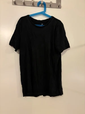 T-shirt - Enkel svart t-shirt med rund hals och korta ärmar. Tillverkad i mjuk bomull, perfekt för en clean och avslappnad stil. Passar till allt och är ett måste i garderoben.