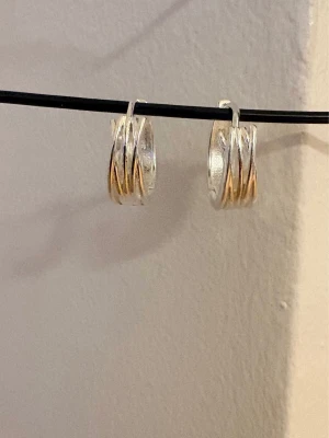 Snygga silverfärgade hoops - Stilrena örhängen i creolmodell, lite bredare med unika detaljer som korsar över ytan. Örhängena har en modern och trendig design som passar till många olika stilar.