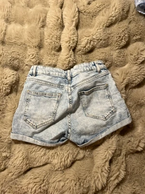 Ljusblå shorts  - Säljer ett par ljusblå shorts från Lindex med  uppvikta benslut. Shortsen har normal passform. Perfekta för varma dagar och enkel att matcha med olika toppar. 