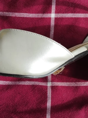 Vita pumps med öppen tå - Snygga vita pumps med rem bak och låg klack. Skon har en stilren design med slät ovandel i konstläder och svart sula. Perfekta för dig som vill ha en klassisk och enkel sko till din outfit.