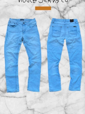 Nudie Jeans - Lean Dean - W33 L32 - Snygga blå jeans från Nudie Jeans Co med klassisk femficksmodell och raka ben. Jeansen har bälteshällor, knappgylf och svarta detaljer vid fickorna. Tillverkade i bomull för en bekväm känsla och stilren look. Priset är diskuterbart!