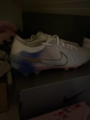 Nike vita och blå fotbollsskor - Snygga fotbollsskor från Nike i vitt med blå och rosa detaljer.  Helt nya aldrig använda. Ny pris 2300kr kvitto finns