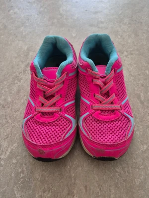 Sneakers - Snygga sneakers i starkt rosa mesh med turkosa detaljer och innersula. Skorna har vita och grå inslag på sulan samt reflexliknande partier. Perfekta för dig som vill sticka ut med färg på fötterna. Klassisk låg modell med snörning.