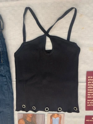 Svart ribbad topp med öljetter  - Svart ribbad topp med öljetter som funkar perfekt till fest. Passar som både XS och S!🖤