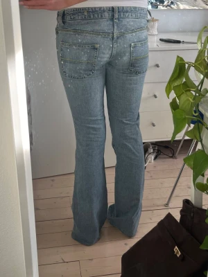 Blå bootcut jeans med låg midja - Säljer ett par ljusblå bootcut jeans med låg midja i denim med en lätt tvättad look. Jeansen är uppsydda, men de är inget man lägger märke till! 