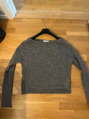 Grå stickad tröja med båtringning - Mysig grå stickad tröja med båtringad hals och långa ärmar. Använd endast en gång.