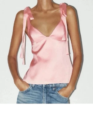 Rosa sidenlinnetopp med knytband - Supersöt rosa linnetopp i siden med breda axelband som knyts till rosetter. Toppen har djup v-ringning och lätt utsvängd passform. Perfekt för dig som vill ha en feminin och trendig look.