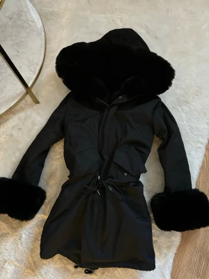 Svart vinterjacka med päls  - Knappt använd, väldigt fint skick! Päls inuti hela jackan så den är väldigt varm och skön! Stor fluffig pälskrage, pälsen vid ärmarna är avtagbar och går att ta bort. Fake päls. Justerbar snörning i midjan så man kan få den mer figursydd om man vill. Storlek XS men passar även S