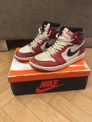 Nike Air Jordan 1 Retro High röd/vit lost and founds  - Nike Air Jordan 1 Retro High sneakers i rött och vitt med svarta detaljer. Klassisk high-top siluett med svart swoosh på sidan, perforerad tåbox och vita skosnören. Ovandel i läder och textilfoder. Ikonisk logga på ankeln och tungans etikett. Jag gör såklart rent dem innan ni köper dem