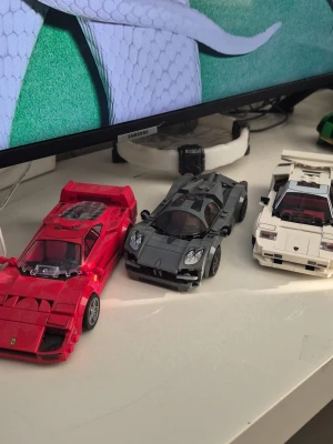 Lego sportbilar Ferrari, Pagani, Lamborghini - Tre detaljerade Lego sportbilar: en röd Ferrari, en grå Pagani och en vit Lamborghini. Alla bilar är byggda av plastklossar och har realistiska former och detaljer som speglar riktiga superbilar. Perfekt för dig som gillar bilar och Lego!
