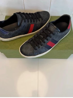 Gucci ace skor - Tja säljer ett par Gucci ace skor i mycket bra skick. Inga defekter förutom att de är lite slitna där bak på den blå detaljen. Hör av dig vid frågor och funderingar