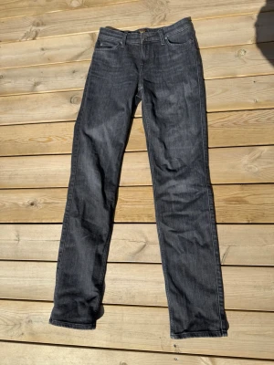 Mörkgrå raka jeans från Lee - Säljer ett par mörkgrå jeans från Lee med klassisk rak passform och fem fickor. Jeansen har snygga kontrastsömmar och är tillverkade i slitstarkt denim-material. Perfekta för dig som gillar en tidlös och enkel stil. W28 L33