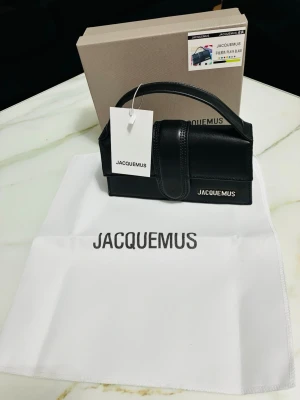 Svart Jacquemus Le Chiquito handväska - Stilren svart handväska från Jacquemus i modellen Le Chiquito. Väskan är tillverkad i slätt läder med ett topphandtag och har en diskret Jacquemus-logga i metall framtill. Kommer med originalbox och dustbag.