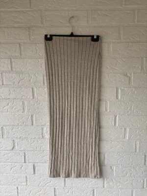 Beige ribbad långkjol från SHEIN - Säljer en beige ribbad långkjol från SHEIN. Kjolen är figurnära och har ett snyggt vertikalt ribbmönster som ger en modern look. Materialet är mjukt och stretchigt med inslag av elastan, vilket gör den bekväm att bära hela dagen.