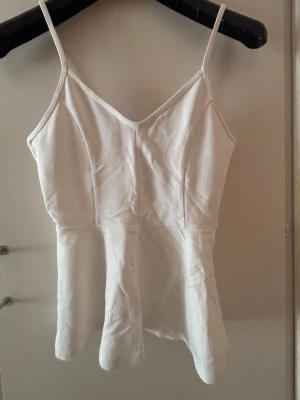 Vit  linnetopp med v-ringning - Säljer en stilren vit linnetopp med smala axelband och v-ringad hals från Gina Tricot. Endast använd ett fåtal gånger. Passar perfekt nu till varmare dagar🌸