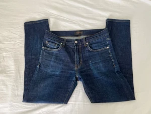 Mörkblå jeans från J.Lindeberg - Snygga mörkblå jeans från J.Lindeberg med klassisk femficksdesign och raka ben. Jeansen har subtila slitningar som ger dem en använd look. Ovanliga, toppen för dig som inte vill vara mainstream. 