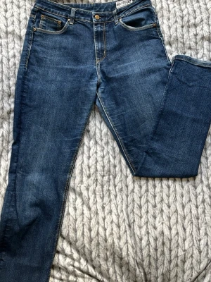 Blå raka jeans från CROCKER - Säljer ett par klassiska blå jeans från CROCKER med slim passform och fem fickor. Jeansen har snygga kontrastsömmar och är tillverkade i ett mjukt denimtyg som sitter skönt hela dagen. Perfekta till alla typer av outfits!