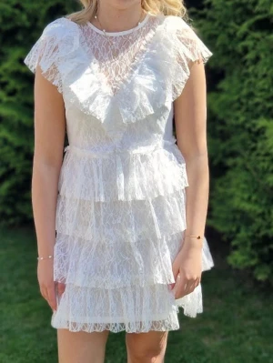 Vit spetsklänning med volanger - Vit spetsklänning från Bubbelroom i storlek S.  Superfin och romantisk modell med volanger och spetsdetaljer, perfekt till sommar, fest eller student. Klänningen har en smickrande passform och stängs med knappar bak.  Använd få gånger, i mycket fint skick.  Säljes då den tyvärr inte kommer till användning längre.