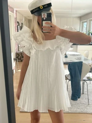 Vit plisserad klänning med volang - Supersöt vit klänning med plisserad kjol och volangärmar. Perfekt för student eller sommaren. Klänningen är som ny. Första två bilderna är lånade, men resten är mina. Kan tänka mig sälja för lägre pris vid snabbt köp. Har även samma klänning i storlek S, bara att gå in på min profil💕💕💕