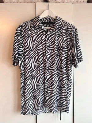 Zebramönstrad skjorta Black Label. S - Säljer en riktigt snygg zebramönstrad skjorta från The Black Label Collection. Lager 157. Skjortan är svartvit med klassisk krage, korta ärmar och knäppning framtill. 