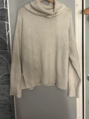 Beige polotröja från Vero Moda - Mysig beige stickad polotröja från Vero Moda med bred ribbstickad kant vid ärmslut och nederkant. Tröjan har en hög, lös polokrage och är tillverkad i mjukt material som passar perfekt för kyliga dagar. Har haft ett hål i sig men inget som syns, priset går att diskutera 💕