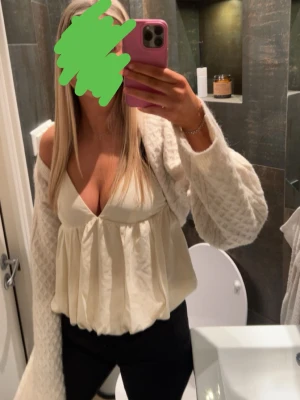 Vit balongtopp med v-ringning - Säljer en vit topp med djup v-ringning och lös passform. Toppen är ärmlös och har ett lätt, flowy material som ger en avslappnad men ändå chic look. Perfekt att styla med jeans eller kjol för en trendig outfit.