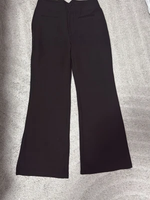Svarta vida kostymbyxor - Säljer ett par svarta kostymbyxor med vida ben och hög midja. Byxorna har två fuskfickor fram och stängs med knapp och dragkedja. Storlek M men passar S också för en vidare look. 