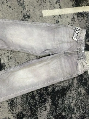 Gråa wide leg jeans Jack & Jones - Säljer ett par gråa wide leg jeans från Jack & Jones. Jeansen har en tvättad look, raka och breda ben samt klassiska fem fickor. Materialet är denim i bomull och passformen är avslappnad och trendig.