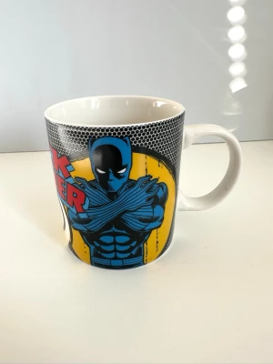 Black Panther mugg - Marvel - Cool mugg / kopp med Black Panther-motiv från Marvel. Muggen är vit med tryck i svart, blått, gult och rött. Tillverkad av Marvel Ceramics. Som ny!
