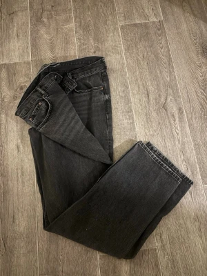 Svarta raka jeans med hög midja - Säljer ett par svart/gråa jeans med rak passform från Gina Tricot. Jeansen är tillverkade i ett kraftigare denimtyg, har en fantastisk tvättning och sitter perfekt i längen på mig som är lite längre. Storlek: 44, används fåtal gånger. 
