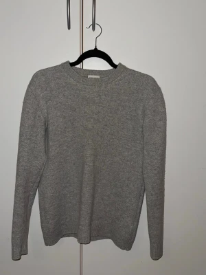 John Henric sweatshirt 10% Kashmir  - En enkel och stilren grå stickad tröja med rund hals och långa ärmar. Tröjan är gjord i mjuk ullmix och har ribbade muddar vid ärmslut och nederkant. Perfekt för lager på lager och passar till det mesta. Den skulle kunna passa någon med storlek S också. 