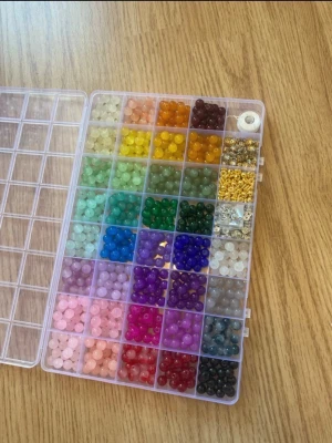 Pärlset i regnbågens färger - Säljer ett stort pärlset med runda pärlor i massor av färger, perfekt för att göra egna smycken. Setet innehåller även små guldfärgade detaljer och elastisk tråd. Allt ligger i en praktisk plastask med fack för varje färg.