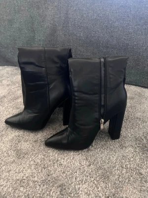Svarta höga boots med klack - Säljer ett par svarta boots från BooHoo. Strl 37 Snyggt minimalistisk design som passar till många outfits.