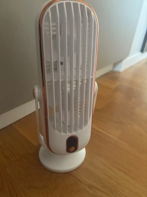 Vit bordsfläkt med kopparfärgade detaljer - Snygg och kompakt bordsfläkt i vitt plastmaterial med kopparfärgade detaljer. Fläkten har en oval form och står på en rund fot. Perfekt för skrivbordet eller nattduksbordet när du vill ha lite extra svalka.