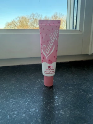 Lanolips 101 Ointment Raspberry Sherbet - Läppbalsam från Lanolips i smaken Raspberry Sherbet. Tuben är rosa med vita detaljer och har ett lekfullt mönster av små rosa prickar. Produkten kommer i en smidig tub som är lätt att ta med sig och applicera. Perfekt för att återfukta torra läppar med en söt doft.