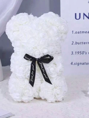 Vit rosbjörn med svart rosett - Säljer en dekorativ björnformad figur täckt av vita konstgjorda rosor och prydd med en svart rosett med texten 'Just for you'. Perfekt som present eller inredningsdetalj. Materialet är plast och tyg.