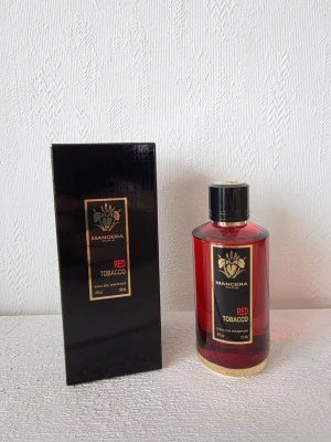 Mancera Red Tobacco EdP 120ml - Mancera Red Tobacco Eau de Parfum i en lyxig röd glasflaska med svart och gulddetaljer. Flaskan rymmer 120 ml och har en elegant svart kork. Förpackningen är svart med gulddetaljer och matchar flaskans exklusiva design.