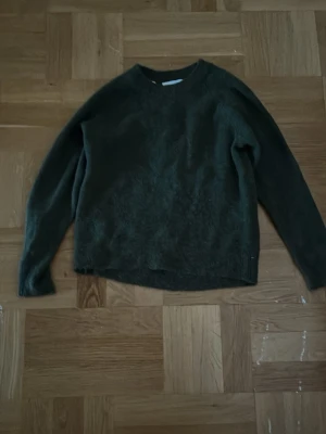 Mörkgrön stickad tröja - Mysig mörkgrön stickad tröja med rund halsringning och långa ärmar. Tröjan har en enkel och avslappnad passform. Använd 1 gång!!