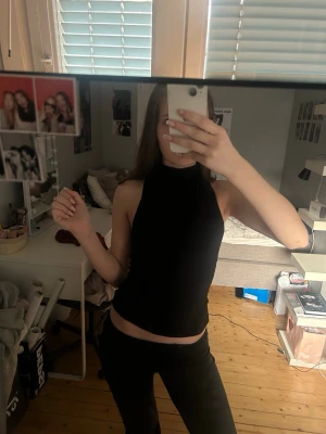 Svart halterneck topp - Snygg svart halterneck-top med hög hals och ärmlös design. Toppen har en tight passform och är perfekt att styla med jeans eller kjol. Enkel och stilren look som passar till många outfits. Aldrig använt 🤍