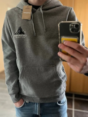 Patagonia hoodie med tryck - Säljer en grå hoodie från Patagonia med stor bergsdesign och texten 'BUILT TO ENDURE' på ryggen samt mindre logga på bröstet. Storleken är XS men sitter som en vanlig S! Hoodien är aldrig använd och lappen sitter kvar såklart. Hoodien har huva med dragsko och en stor magficka. Ord pris ca 100£😁pris går att diskutera!😁