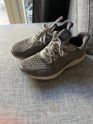 Adidas Alphabounce storlek 37 1/3 - Snygga grå Adidas Alphabounce sneakers med stickad mesh-överdel och vita detaljer på sidan av sulorna. Undersidan av sulorna är svarta. Storlek 37 1/3 . 