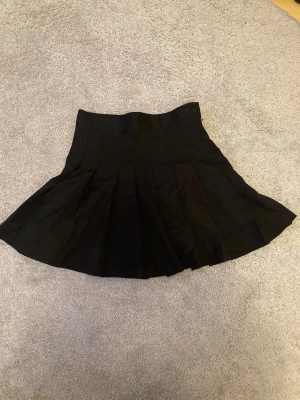 Gullig svart kjol!  - Kort gullig kjol från monki i storlek 36. Dragkedja och knapp på sidan om. Använt endast någon enstaka gång så ännu i mycket bra skick! 