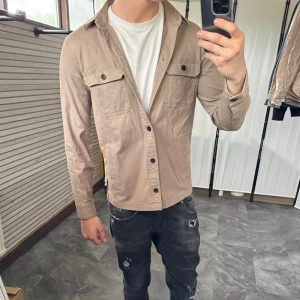 Beige overshirt med fickor - Perfekta overshirten, tunn, prima passform och beige‼️Mycket fint skick, inga defekter. Passar dig som är 170-180cm ungefär. Modellen är 185 cm, 75 kg. Skriv för mer information!🤝