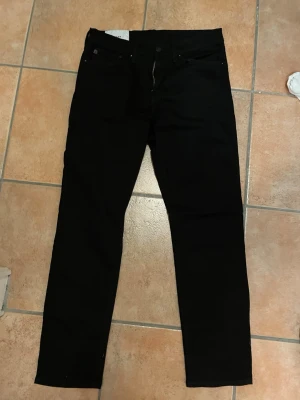 Svarta raka jeans H&M 43/32  - Helt nya jeans ifrån HM endast provade 1 gång, med rak passform och klassisk femficksdesign. Jeansen har normal midja och stängs med dragkedja och knapp. Perfekta för en clean och stilren look. Materialet är bomullsdenim. Säljes under halva nypriset. 