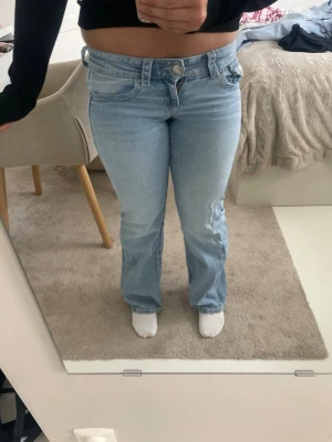 Ljusblå bootcut jeans - Säljer ett par ljusblå bootcut jeans med klassisk femficksdesign och normal midja. Jeansen har en avslappnad passform över benen och är tillverkade i denim. I storlek 146