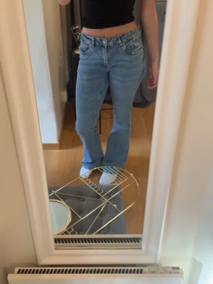 Ljusblå bootcut jeans  - Säljer ett par ljusblå bootcut jeans med pärldetaljer på bakfickorna. Jeansen har klassisk femficksdesign, låg midja och är tillverkade i denim. Perfekta för en trendig och avslappnad look. Midjemåttet rakt över är 37 cm och innerbens längden är 78 cm. Det är inte fast pris utan går att sänka💕